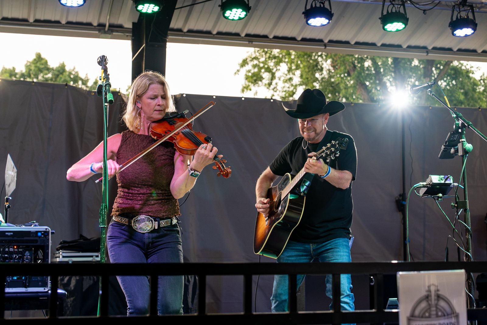 Fiddle and acoustic guitar mid-song under festival stage lights