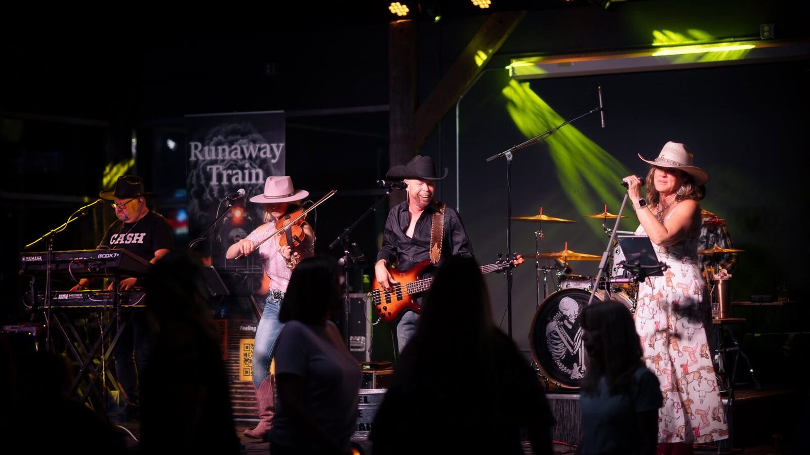 Runaway Train full band performing on stage under green stage lights