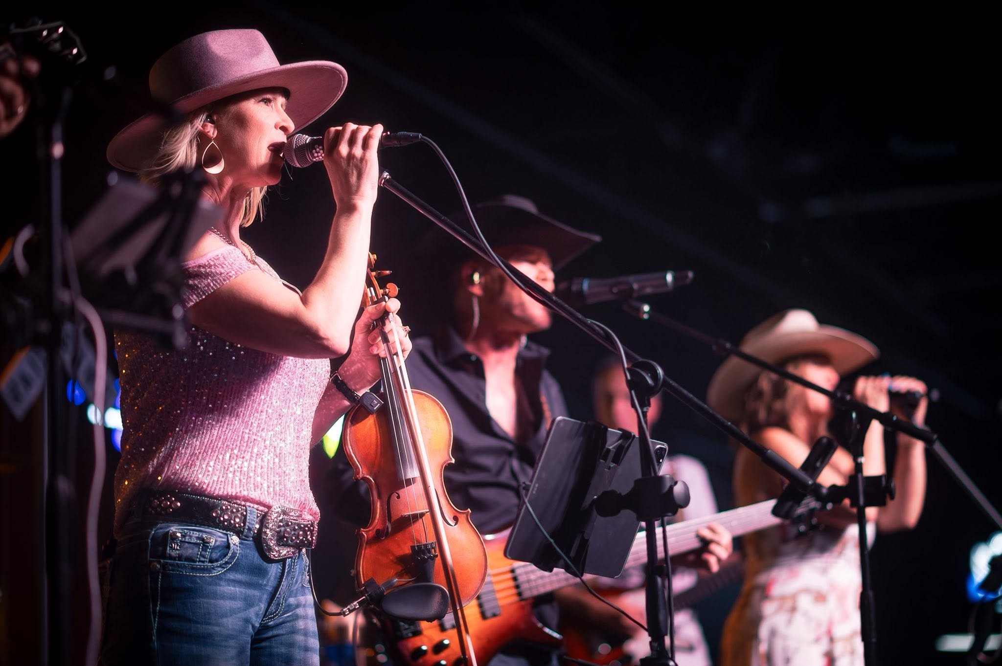 Runaway Train vocalists and fiddle under stage lights